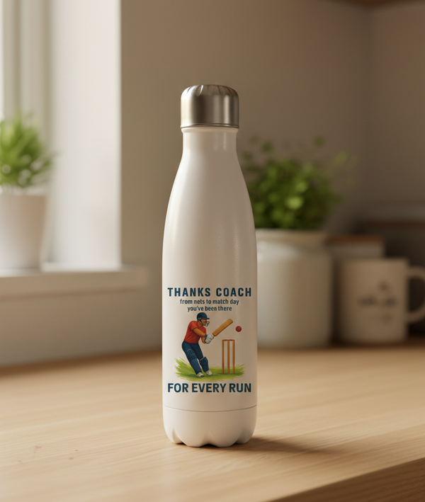 White water bottle with a printed design on a wooden surface. This is a Cows Corner water bottle with a funny cricket slogan 'Thanks Coach From Nets To Match Day You’ve Been There for Every Run'. Cows Corner gifts are perfect for sport-mad fans, these gifts work brilliantly for birthdays, new baby celebrations, Father’s Day, Mother’s Day, Christmas, anniversaries, thank you gifts, end-of-season team awards, graduations, retirements, and just-because moments when you want to raise a smile. 
