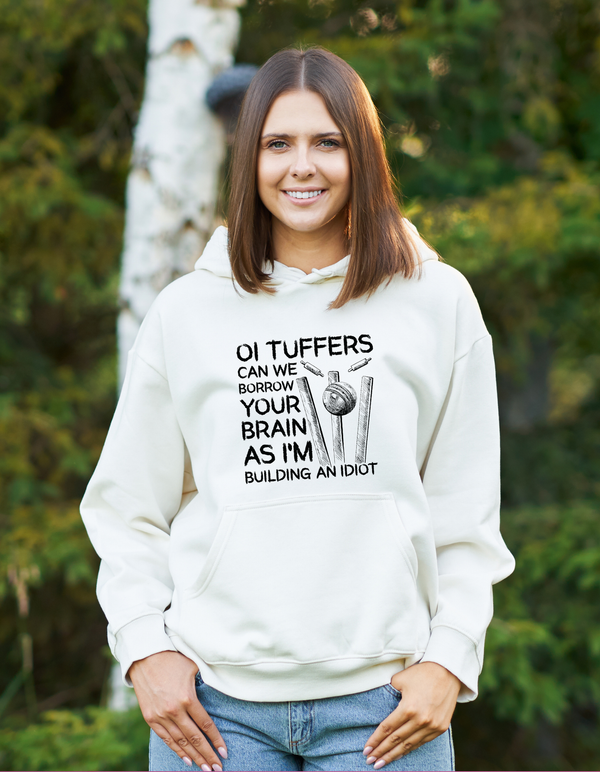 A man wearing a white hoodie with Oi Tuffers, can we borrow your brains as I'm building an idiot, on the front.  Funny Cricket Hoodie, Premium Fabric, Multiple Adult Sizes