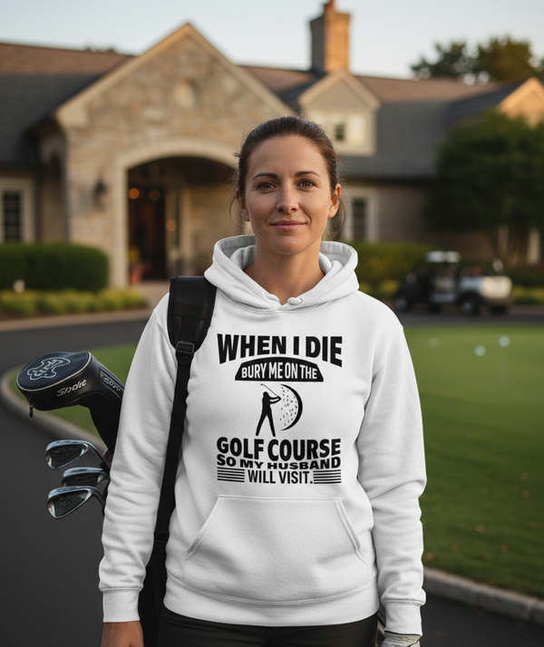 Woman wearing a hoodie with a humorous golf-themed message on a golf course. The lady is wearing a Cows Corner hoodie with the funny golf slogan 'When I Die Bury Me on the Golf Course So My Husband Will Visit'. Cows Corner gifts are perfect for sport-mad fans, these gifts work brilliantly for birthdays, new baby celebrations, Father’s Day, Mother’s Day, Christmas, anniversaries, thank you gifts, end-of-season team awards, graduations, retirements, and just-because moments when you want to raise a smile. 
