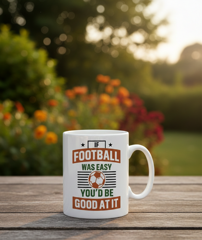 White mug with a humorous football quote on a wooden table outdoors. This is a Cows Corner mug with a funny football slogan 'If Football Was Easy You’d Be Good at It'.  Cows Corner gifts are perfect for sport-mad fans, these gifts work brilliantly for birthdays, new baby celebrations, Father’s Day, Mother’s Day, Christmas, anniversaries, thank you gifts, end-of-season team awards, graduations, retirements, and just-because moments when you want to raise a smile. 
