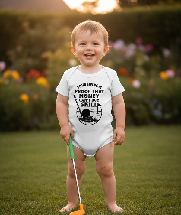 Child wearing a onesie with a golf-themed message, standing in a garden.  The baby is wearing a Cows Corner baby grow with a funny golf slogan 'Your Swing Is Proof That Money Can’t Buy Skill'. Cows Corner gifts are perfect for sport-mad fans, these gifts work brilliantly for birthdays, new baby celebrations, Father’s Day, Mother’s Day, Christmas, anniversaries, thank you gifts, end-of-season team awards, graduations, retirements, and just-because moments when you want to raise a smile. 

