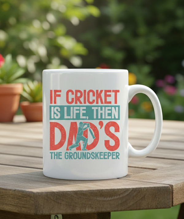 White mug with cricket-themed text on a wooden table outdoors. This is a Cows Corner mug with a funny cricket slogan 'If Cricket Is Life, Then Dad's The Groundkeeper'.  Cows Corner gifts are perfect for sport-mad fans, these gifts work brilliantly for birthdays, new baby celebrations, Father’s Day, Mother’s Day, Christmas, anniversaries, thank you gifts, end-of-season team awards, graduations, retirements, and just-because moments when you want to raise a smile. 
