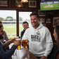 People in a pub watching cricket on TV, one person wearing a Cows Corner t-shirt with the funny cricket slogan 'Club Cricket where Everyone’s an All-Rounder'.  Cows Corner gifts are perfect for sport-mad fans, these gifts work brilliantly for birthdays, new baby celebrations, Father’s Day, Mother’s Day, Christmas, anniversaries, thank you gifts, end-of-season team awards, graduations, retirements, and just-because moments when you want to raise a smile. 
