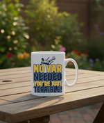 White mug with humorous text design on a wooden table outdoors. This is a Cows Corner mug with a funny football slogan 'No VAR Needed You’re Just Terrible'. Cows Corner gifts are perfect for sport-mad fans, these gifts work brilliantly for birthdays, new baby celebrations, Father’s Day, Mother’s Day, Christmas, anniversaries, thank you gifts, end-of-season team awards, graduations, retirements, and just-because moments when you want to raise a smile. 
